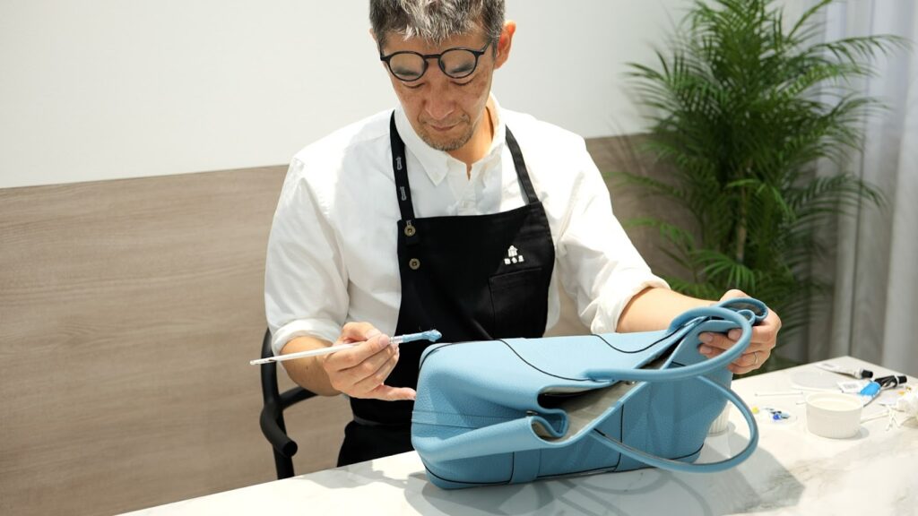 修理スタッフがバッグを修理している